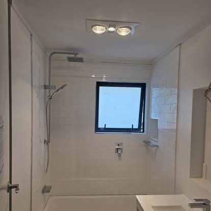 Modern white-tiled bathroom with shower and subway tiles, completed by BMP Plumbers